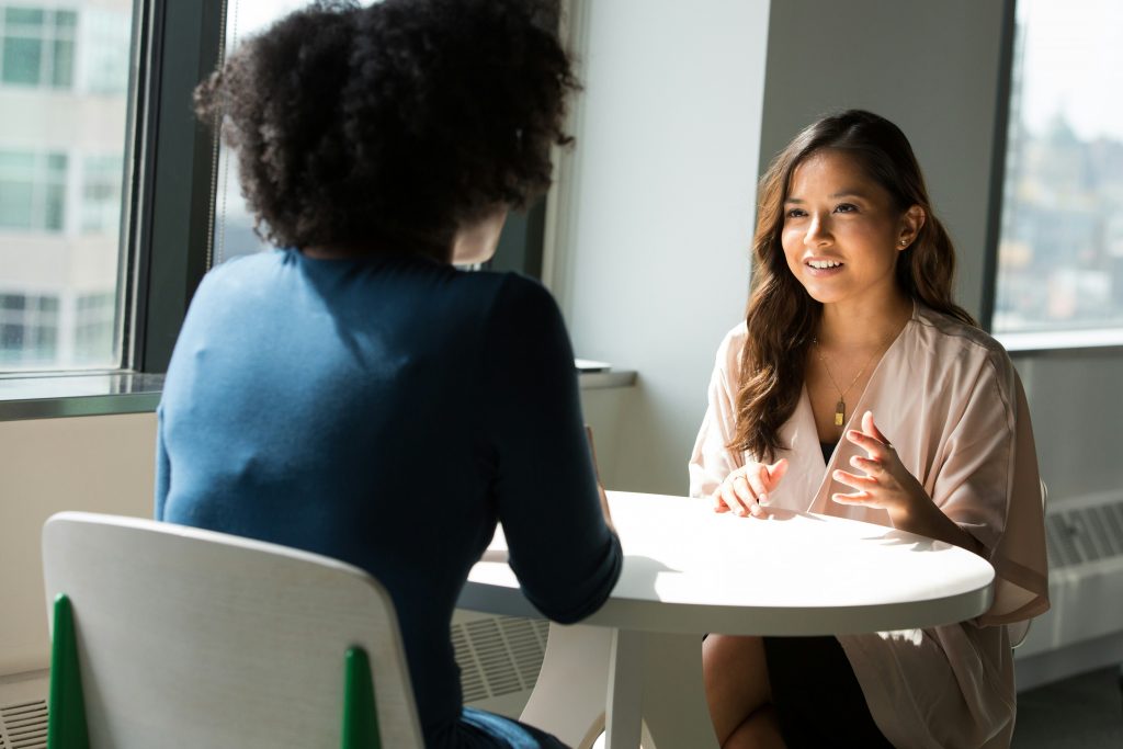 Two women talk across a table